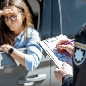 Police officer issuing a traffic fine to a seated woman in a car for a violation